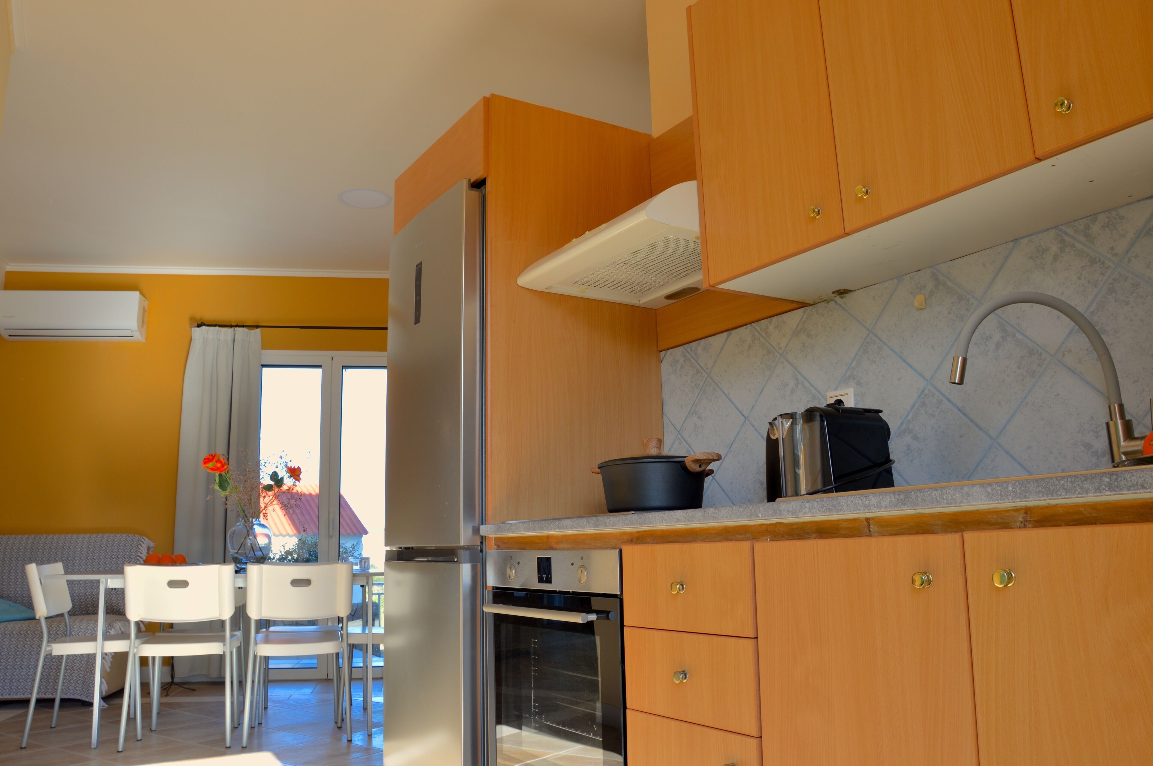 Una cocina compacta con armarios de madera, horno empotrado y ventana con cortinas.