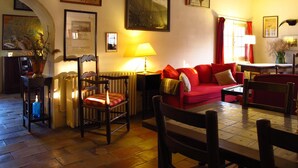 A cozy living room with a red sofa, wooden furniture, and various framed artworks on the walls. - Cacharel (Saintes-Maries-de-la-Mer)