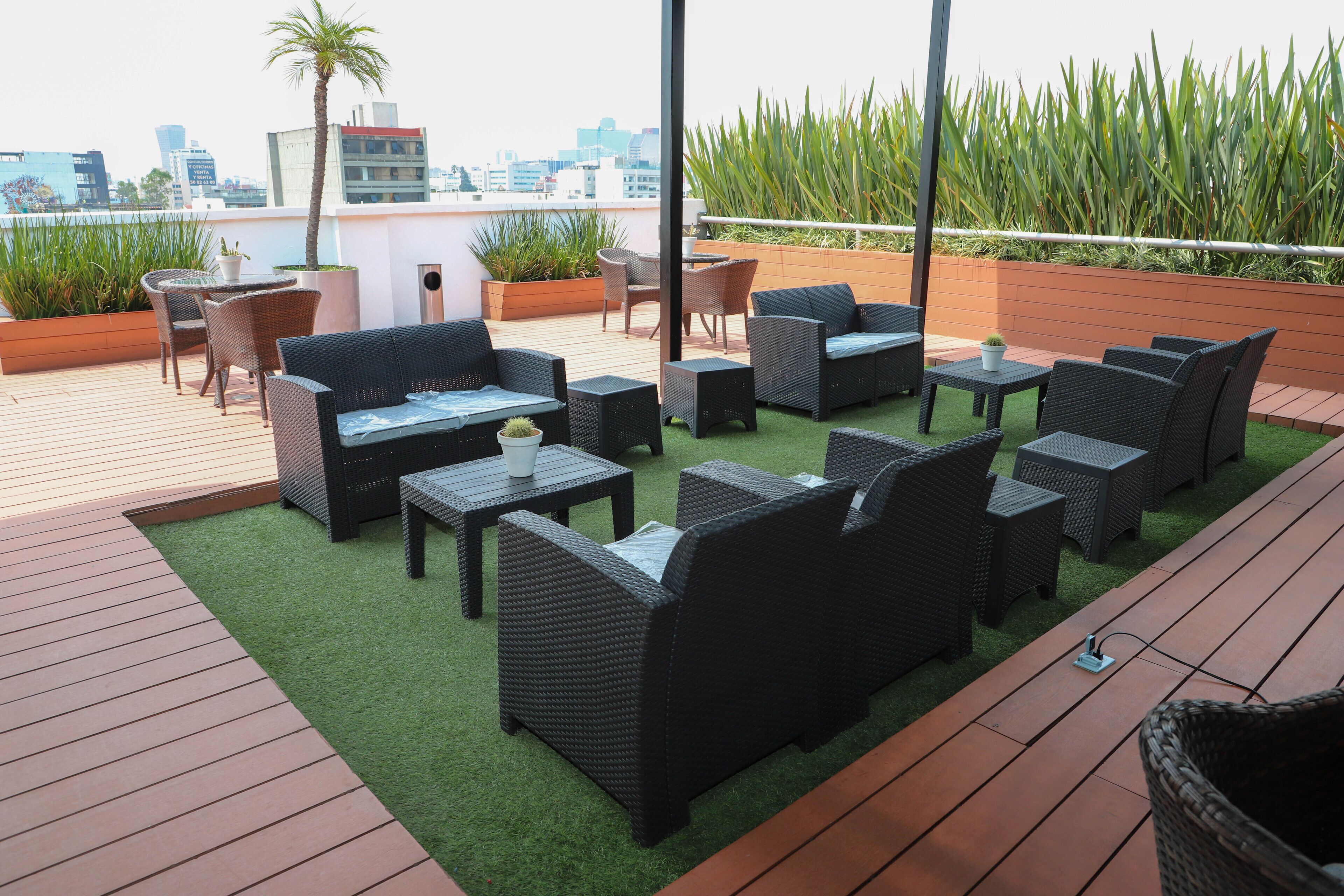 Terraza en la azotea con mobiliario de mimbre, una pequeña mesa y una planta en maceta.