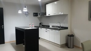 A modern kitchen with white cabinets, a black countertop, and two pendant lights. - Capital St. (Mexico City)