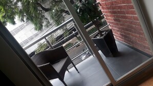 A balcony with a wicker chair and a black planter. - Capital St. (Mexico City)