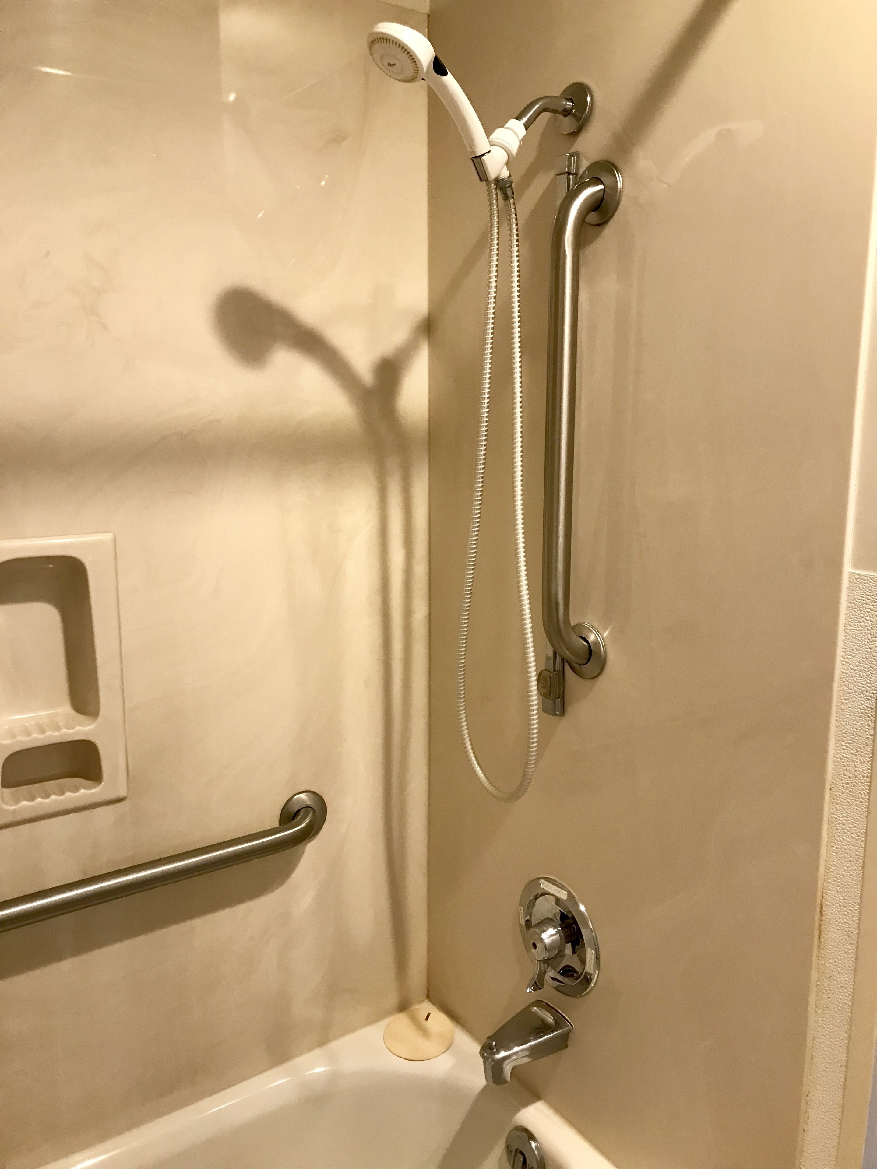 A bathroom with a bathtub, a shower with a handheld showerhead, and a handheld shower attachment.