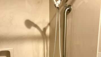 A bathroom with a bathtub, a shower with a handheld showerhead, and a handheld shower attachment.