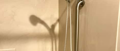 A bathroom with a bathtub, a shower with a handheld showerhead, and a handheld shower attachment.