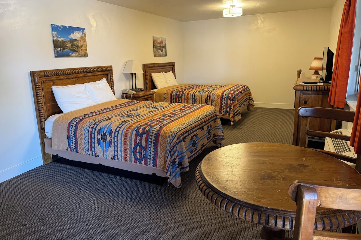 Une chambre d’hôtel avec deux lits, une table en bois et une chaise.