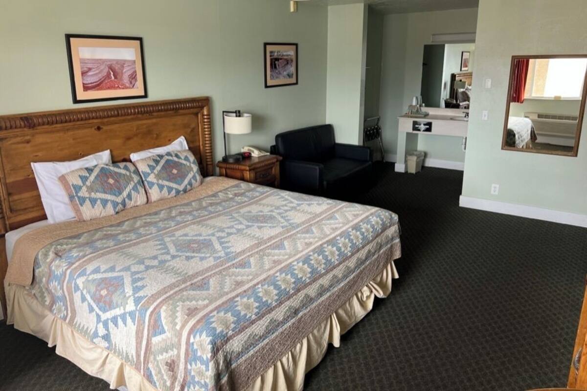 Une chambre d’hôtel avec un grand lit, un bureau, une chaise et un miroir.