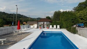 A swimming pool with a white deck, surrounded by lounge chairs and a small building. - Clarketon Motel (Maggie Valley)