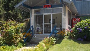A building with a 'OPEN' sign, a porch with steps, and a Coca-Cola sign in the background. - Clarketon Motel (Maggie Valley)