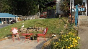 A patio with outdoor furniture, a fire pit, and a garden with yellow flowers. - Clarketon Motel (Maggie Valley)