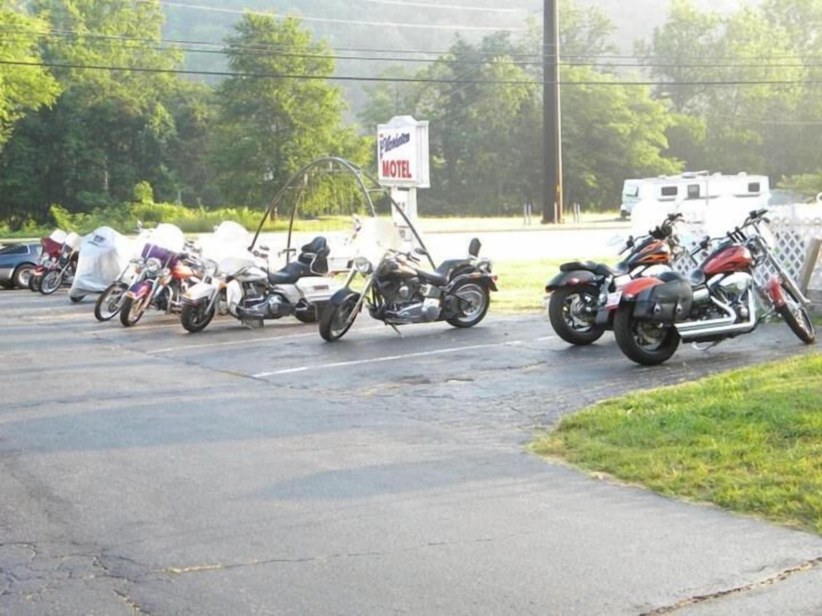 Varias motocicletas estacionadas en un estacionamiento, con un letrero de motel al fondo.