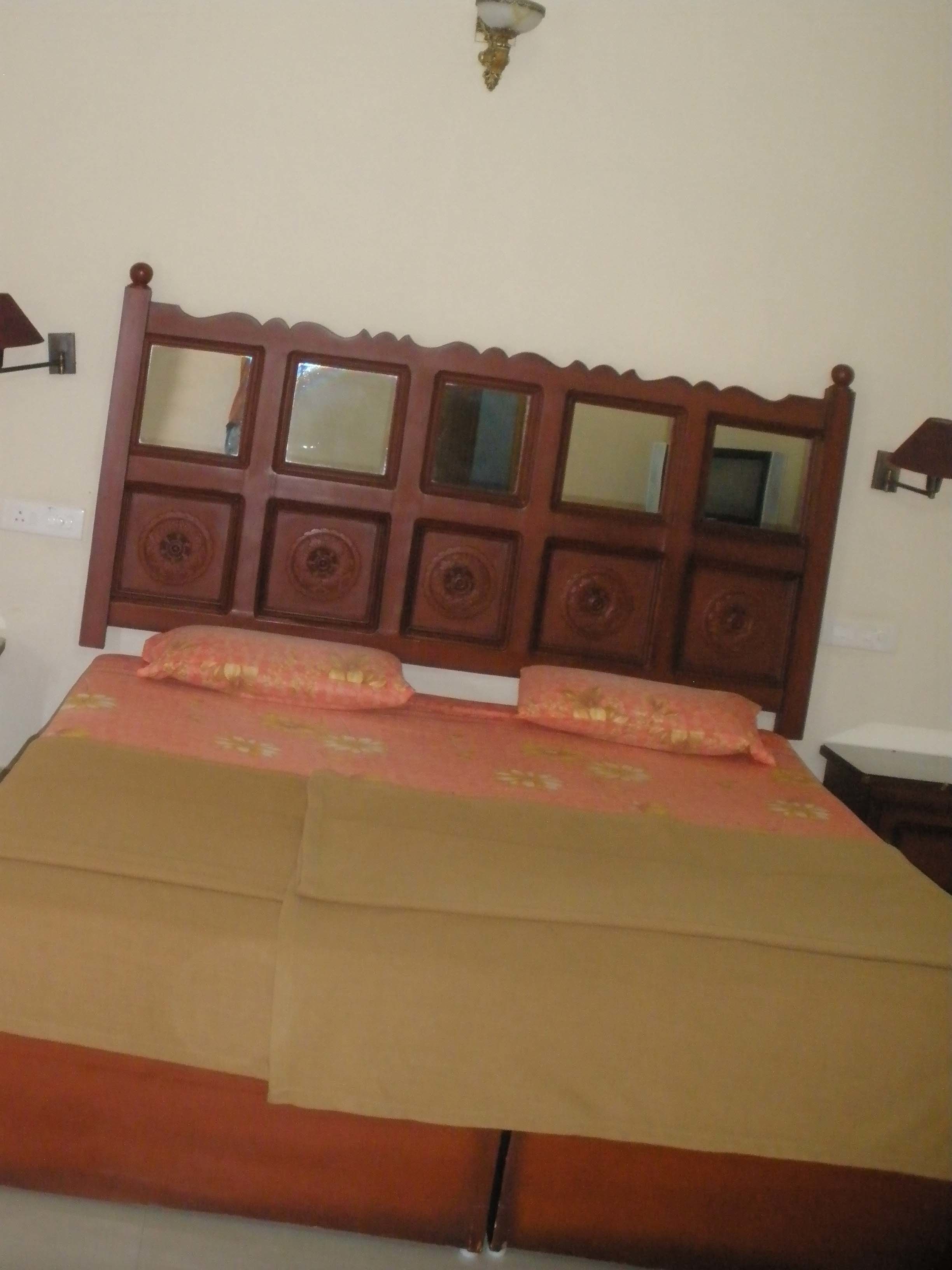 A bed with a wooden headboard featuring multiple rectangular mirrors and decorative panels.