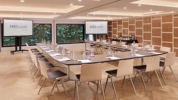 Un salón de conferencias con una mesa larga, sillas y dos pantallas mostrando 'H10 cubik'.