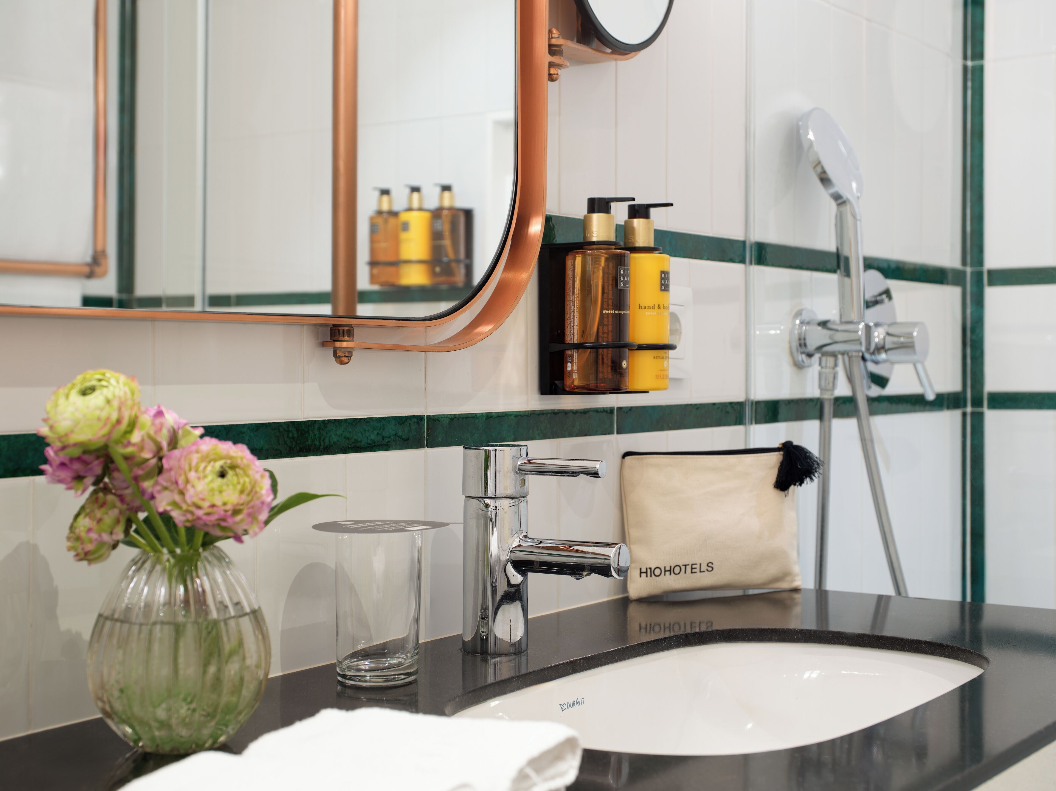 A bathroom with a sink, mirror, and toiletries.