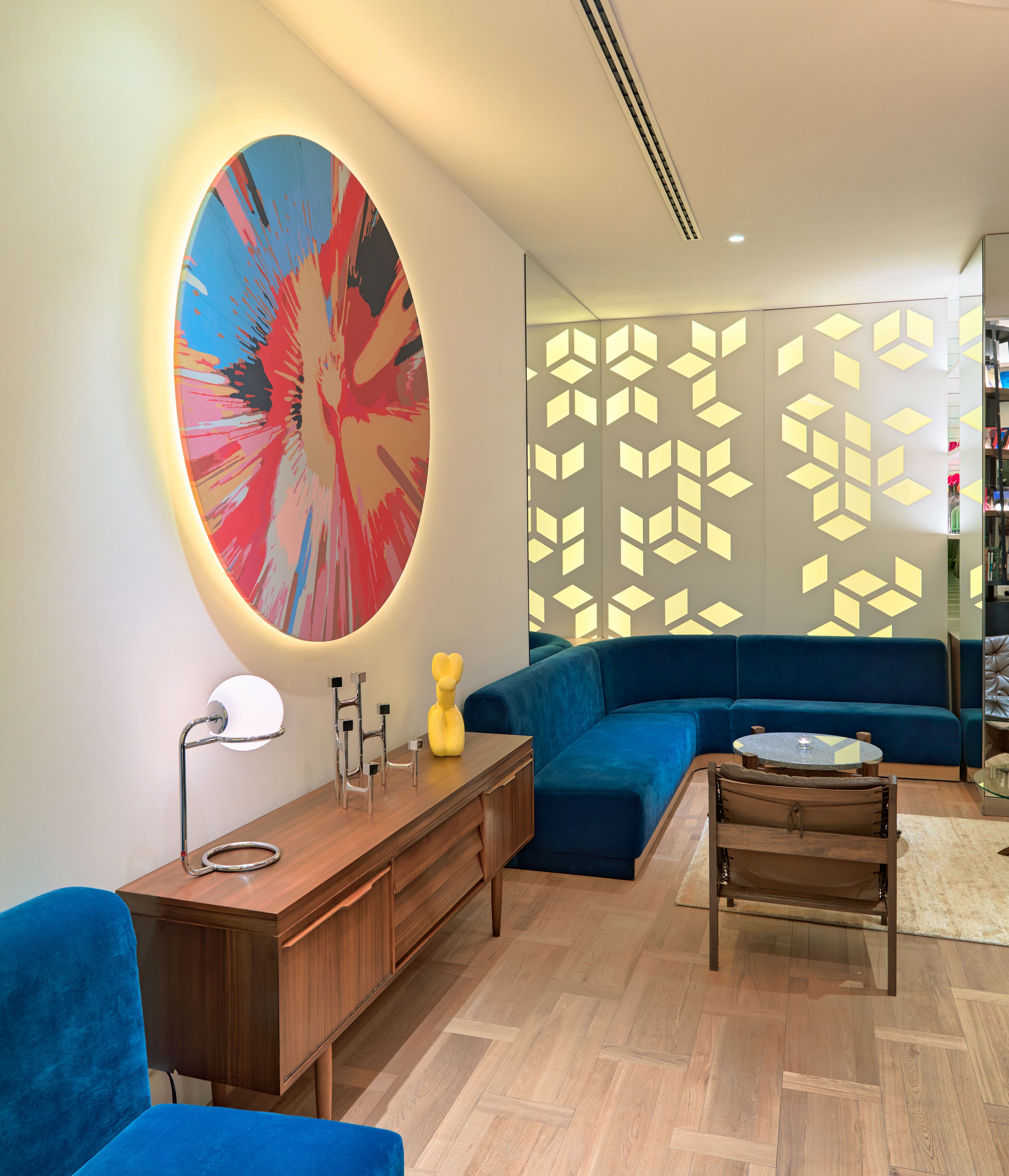 Een moderne woonkamer met een blauwe bank, een houten bijzettafeltje en een groot abstract schilderij.