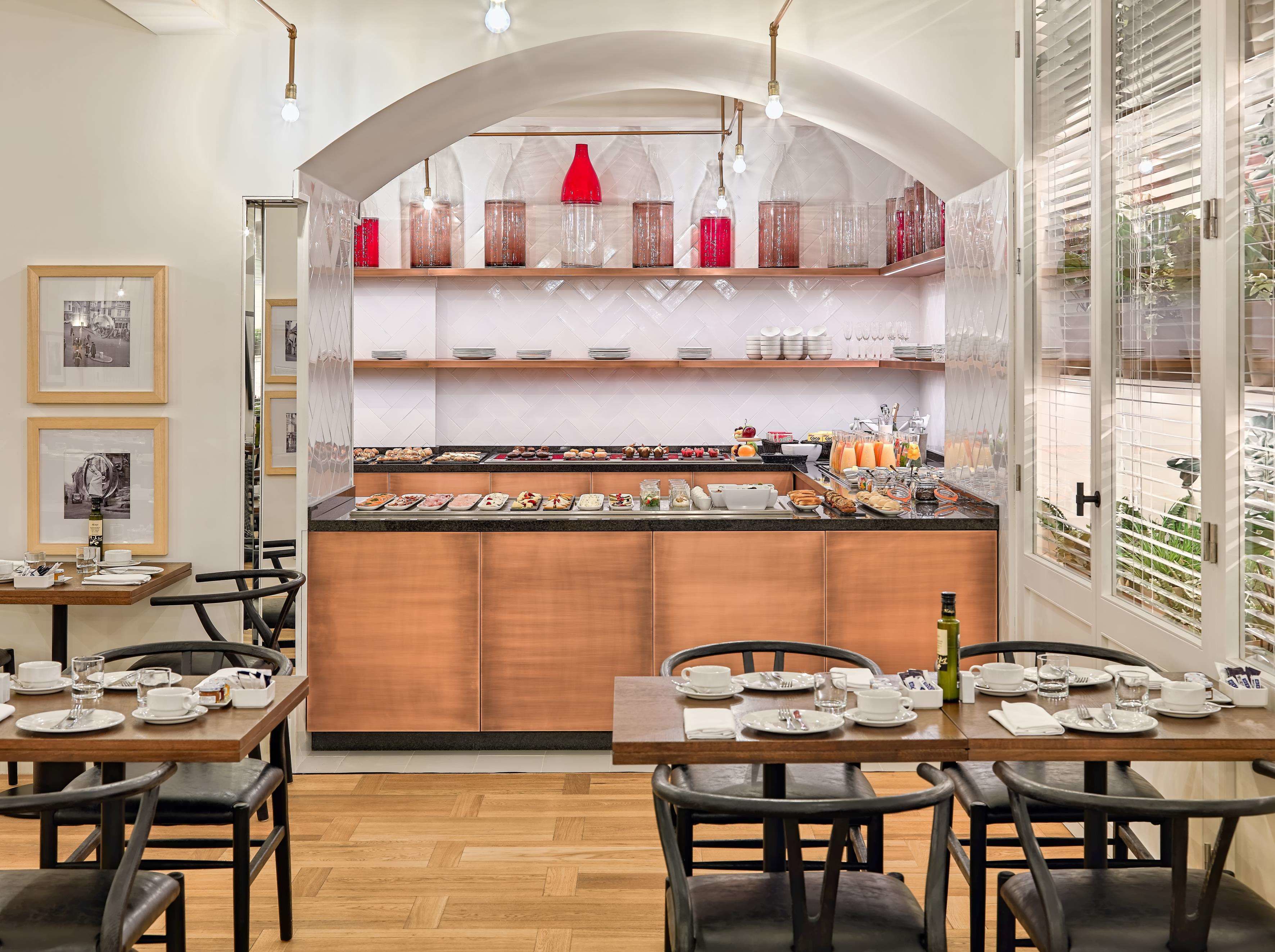 A breakfast buffet area with a variety of food options, a coffee station, and a seating area with tables and chairs.