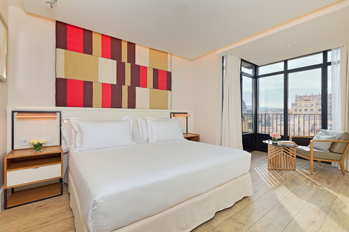 Ein modernes Hotelzimmer mit einem großen Bett, Blick auf die Stadt und einem großen Fenster.