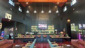 A bar with a wooden ceiling, multiple hanging lights, and a bar counter with bottles and glasses. There are leather booths and tables with chairs. - Bourbon Manor B&B (Bardstown)