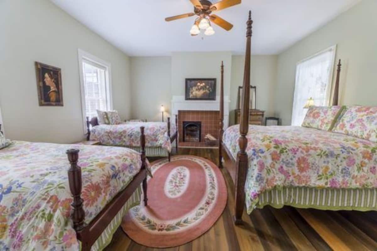 Quarto com duas camas, lareira e ventilador de teto.