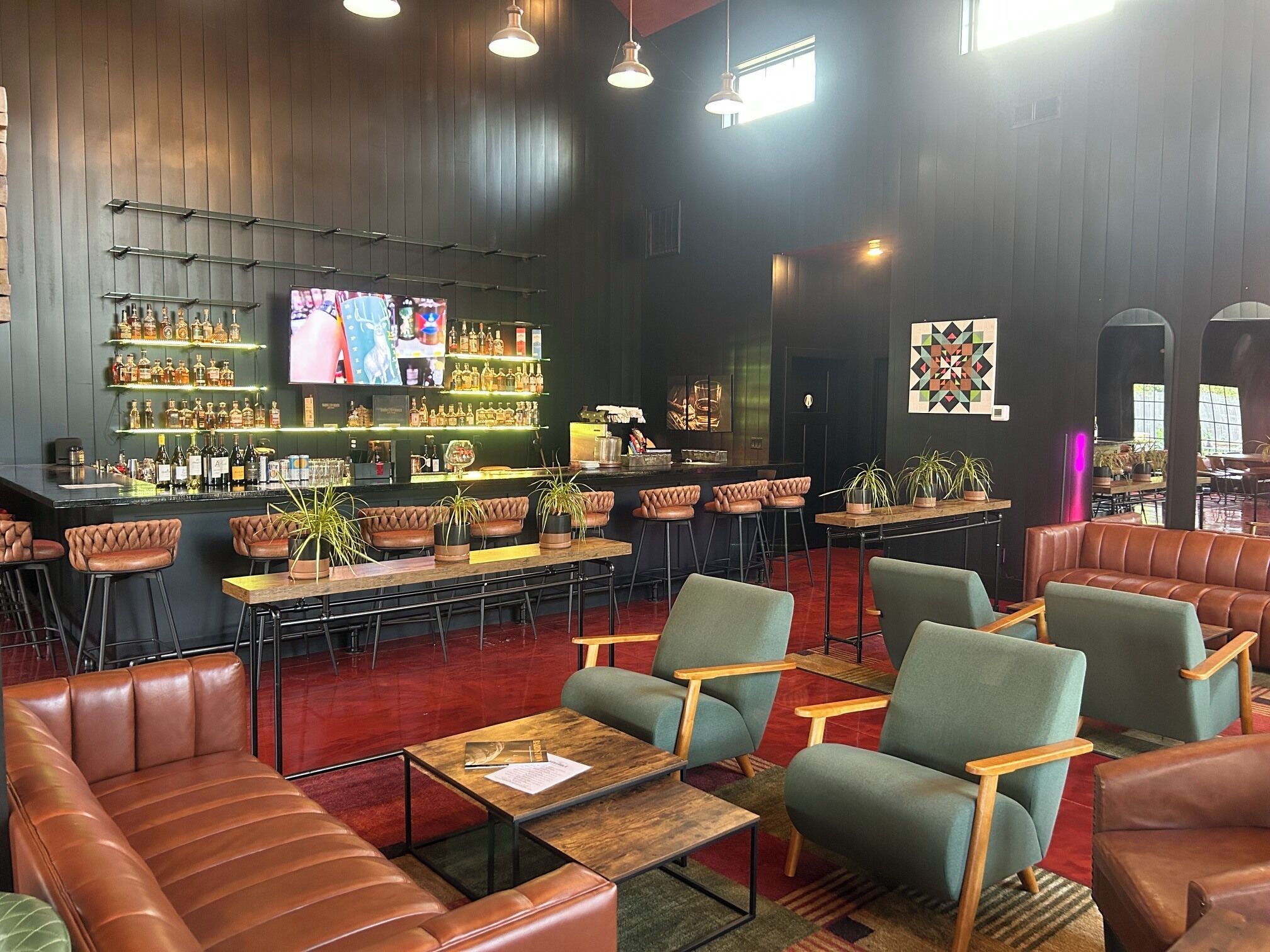 A bar area with leather seating, a TV screen, and shelves of liquor bottles.