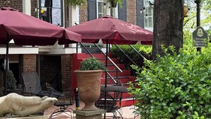 A courtyard with outdoor seating, a stone statue, and a brick building with shutters. - Bourbon Manor B&B (Bardstown)