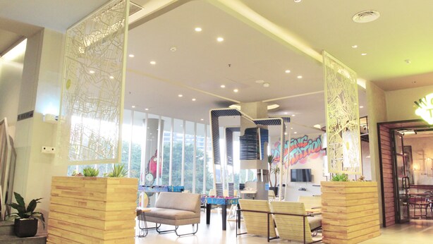 A spacious lobby with a modern design, featuring a reception desk, seating area, and a staircase leading to upper floors.