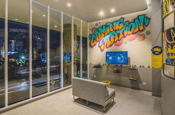 Un intérieur moderne avec une grande fenêtre, un canapé gris et un mur orné de graffitis colorés.