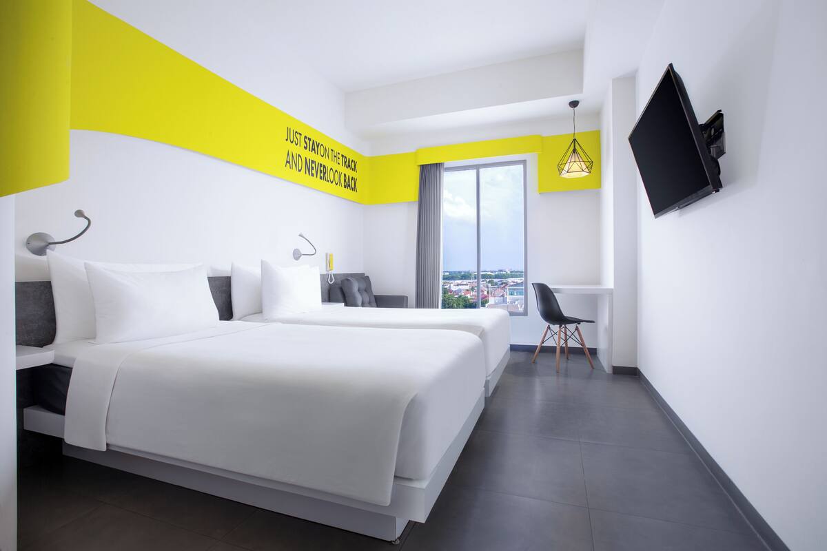 A modern hotel room with a large bed, a desk, and a TV.