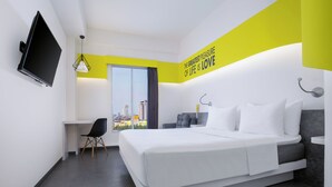 A modern hotel room with a bed, a desk, a chair, a TV, and a large window with a city view.