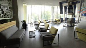 A modern lounge area with seating arrangements, large windows, and a cityscape view.