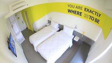 A hotel room with a bed, bedside tables, an air conditioning unit, and a motivational wall message.