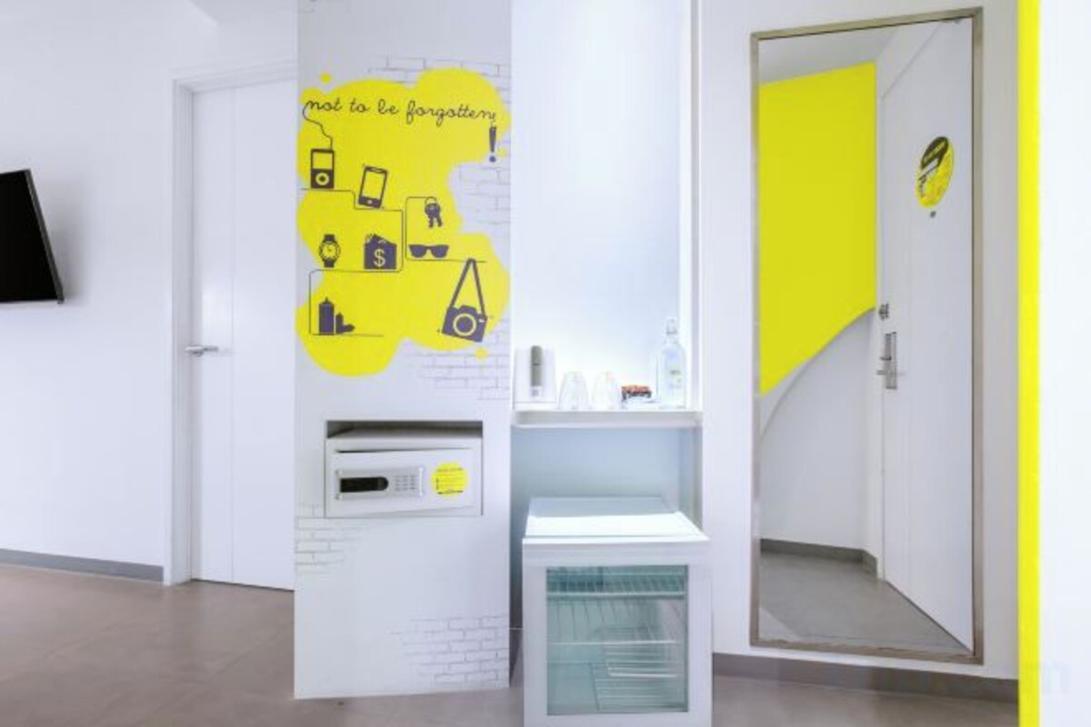 Una habitación con una puerta blanca, una pared de acento amarillo y un pequeño estante con objetos.