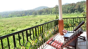A balcony with a view of a lush green landscape and distant hills. - Kerala House (Peermade)