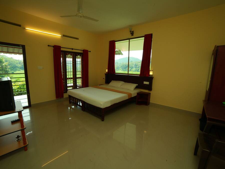 Habitación de hotel con cama, escritorio, silla y vistas al verdor.