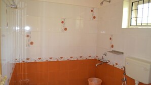A bathroom with orange and white tiles, a shower, a toilet, and a window. - Kerala House (Peermade)