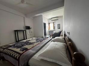 A bedroom with a bed, a bedside table, a chair, and a television.