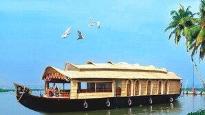 Ein traditionelles Hausboot mit einem reetgedeckten Dach, mehreren Fenstern und einem Deck.
