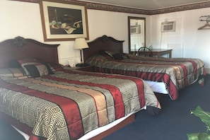 Two single beds with patterned bedspreads, a wooden headboard, and a desk with a chair.