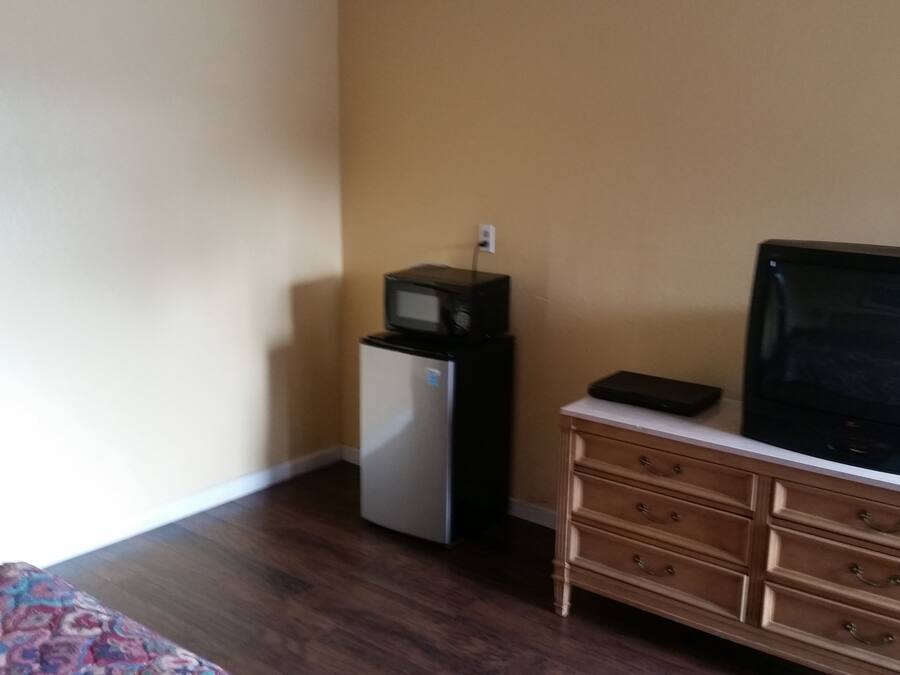 A small room with a wooden dresser, a television, and a refrigerator.