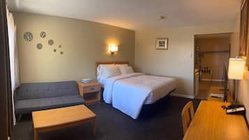 Une chambre d’hôtel comprenant un lit, un canapé, un bureau, une chaise, une table de chevet, une lampe et une petite table.