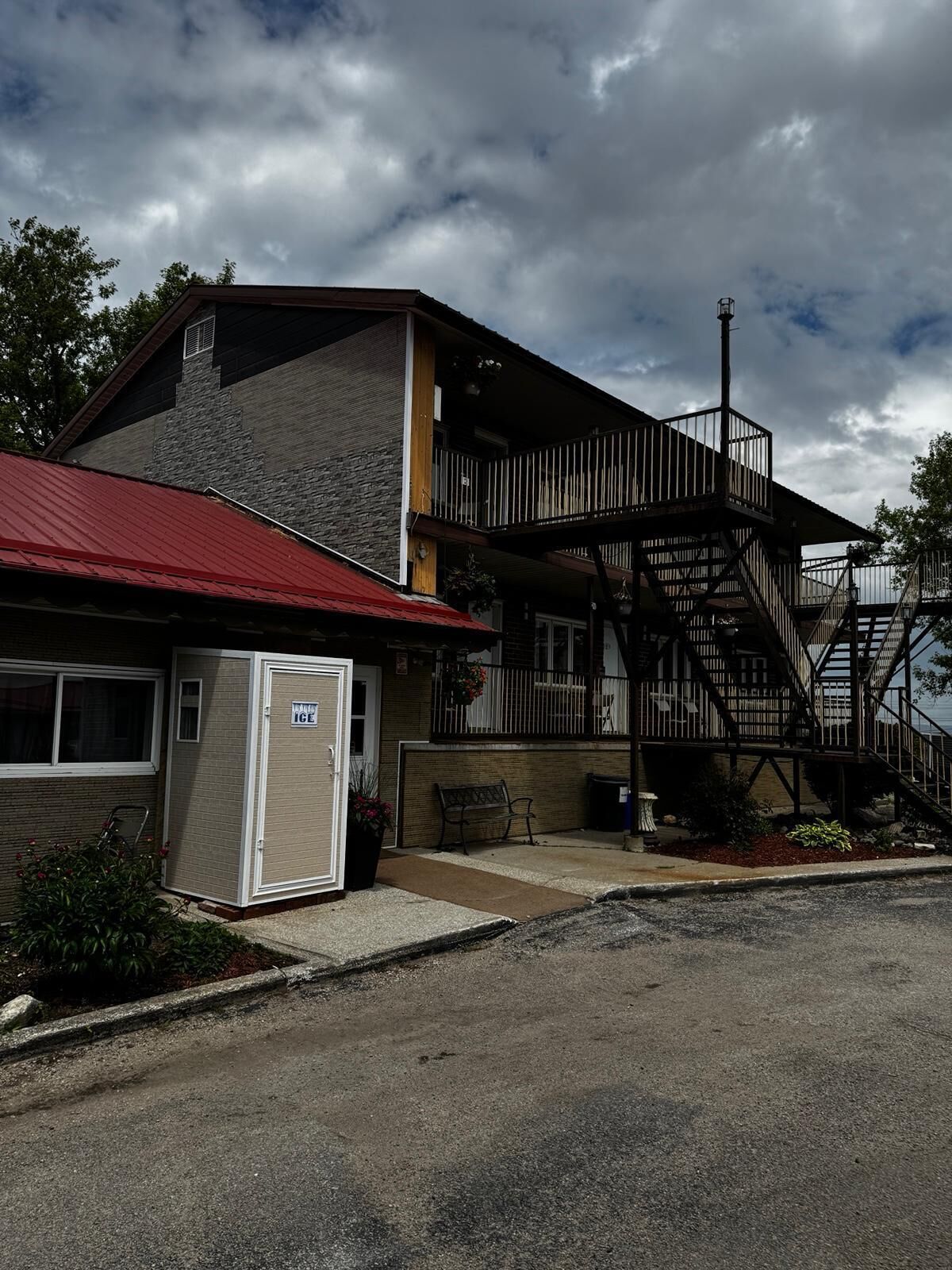 A building with a red roof, a garage, and a staircase leading to a balcony.