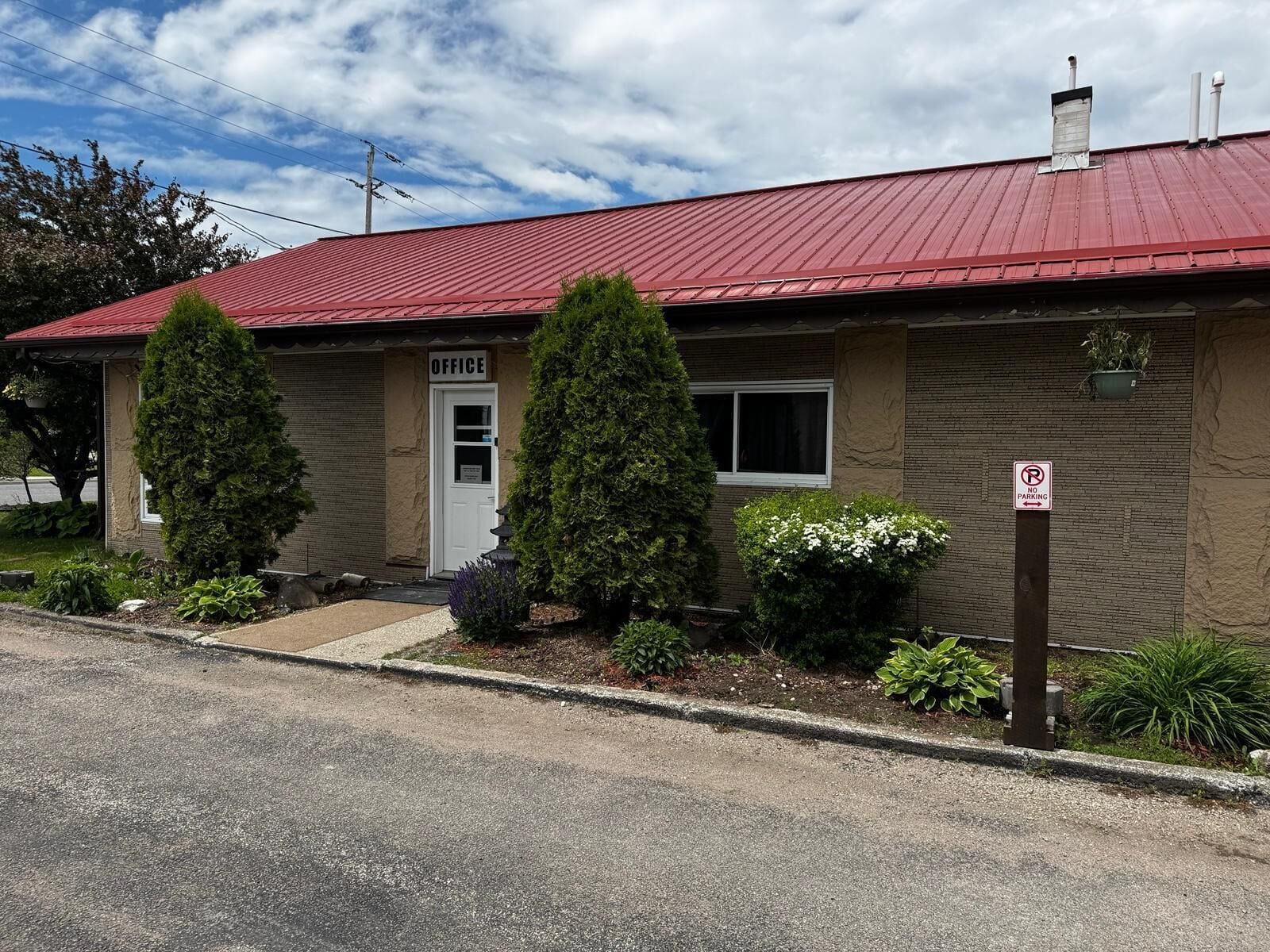 A single-story building with a red roof, a door labeled 'OFFICE,' and a 'NO PARKING' sign.