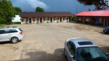 A motel with a red roof, multiple rooms, and a parking lot.