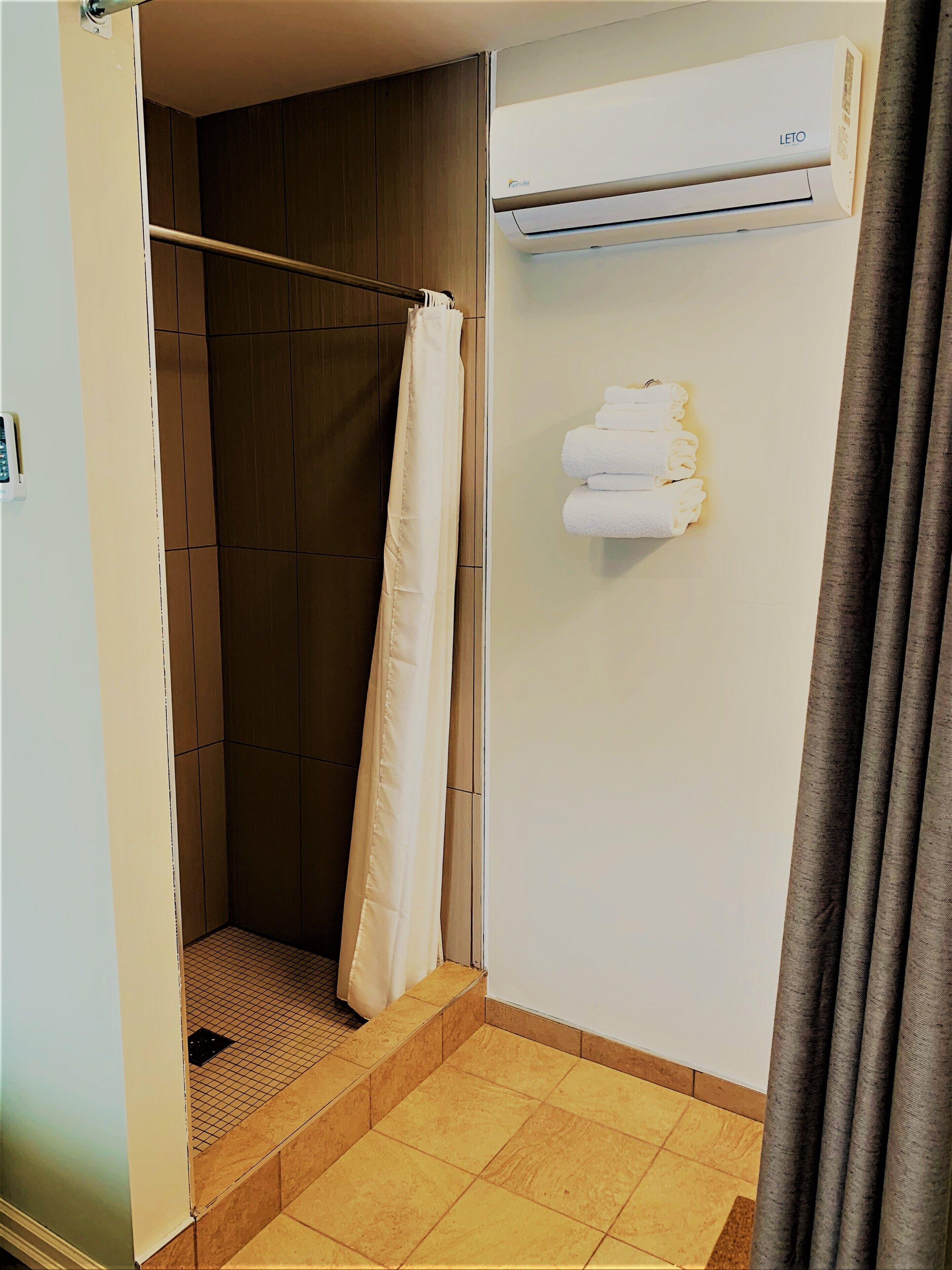 Ein Badezimmer mit Dusche, Handtuchhalter und Klimaanlage.