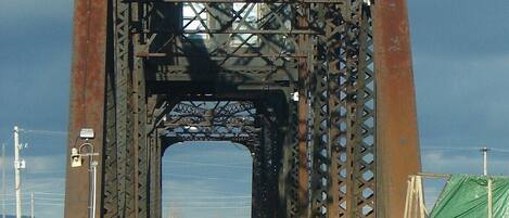 A large metal bridge with a central archway and a road leading through it.