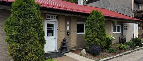A building with an 'OFFICE' sign, a red roof, and a brick facade.