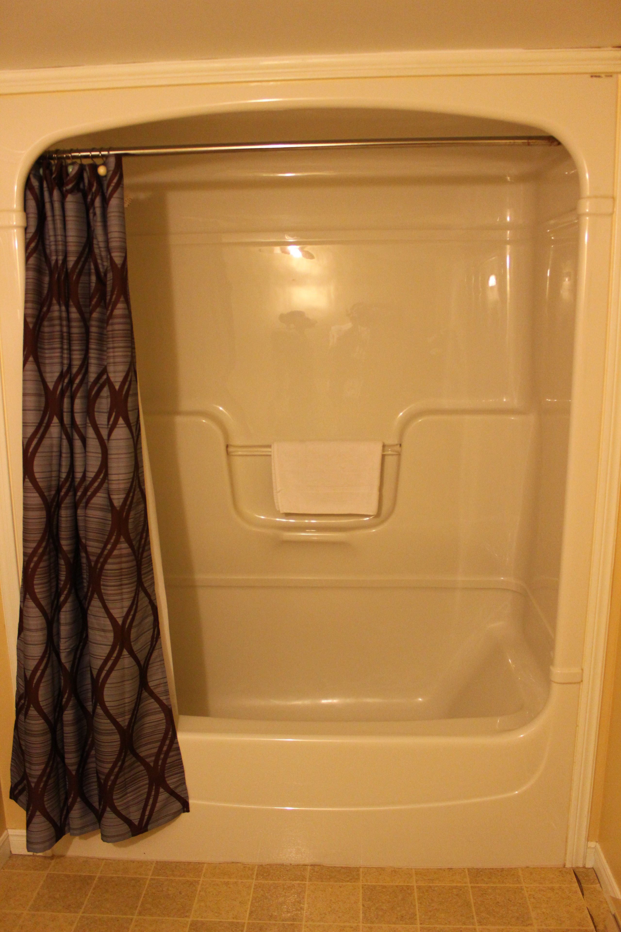 A bathtub with a shower curtain, a towel rack, and a tiled floor.