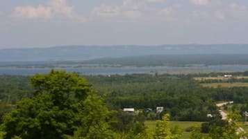 Eine Landschaft mit einem Gewässer, viel Grün und sanften Hügeln in der Ferne.