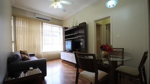 A living room with a sofa, TV, and dining table with chairs.