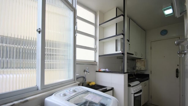 A compact kitchen with a washing machine, a stove, and a sink.