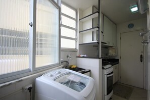 Una cocina compacta con lavadora, estufa y fregadero.